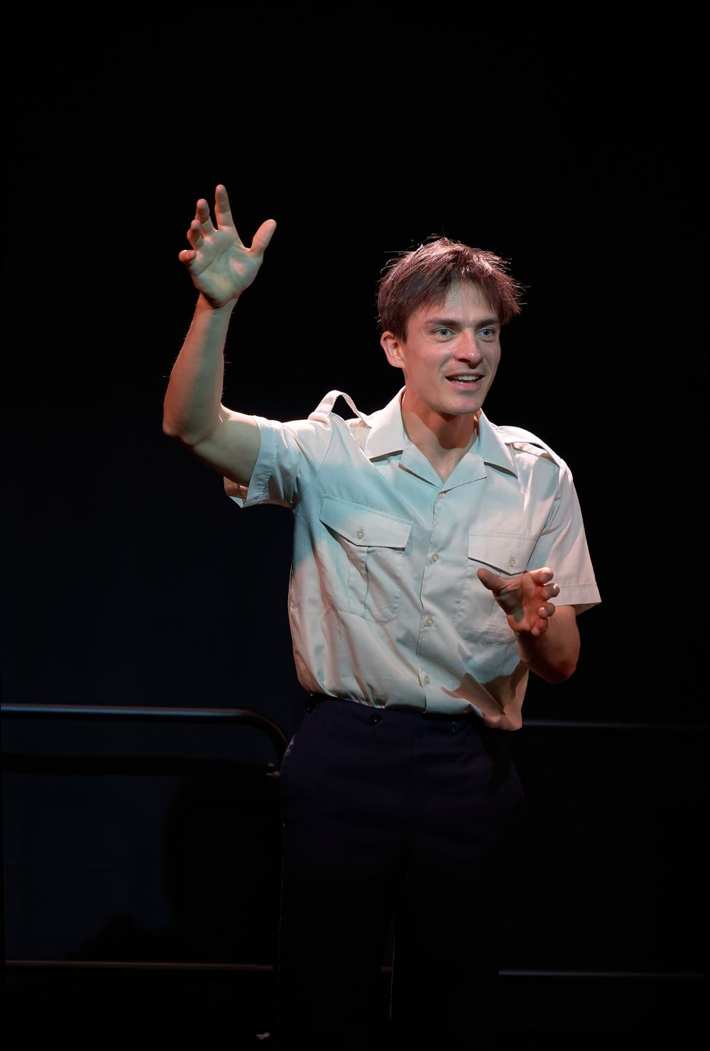 Pierre Devaux en chemise d'aviateur, bras levé, incarne Antoine de Saint-Exupéry sur scène